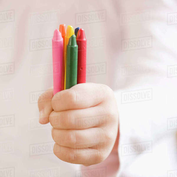 Child holding assorted crayons Stock Photo Dissolve