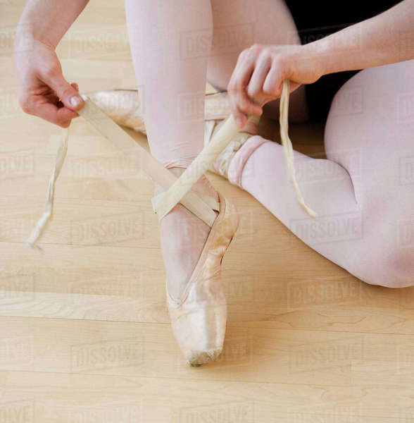 Female ballet dancer tying pointe shoes Stock Photo Dissolve