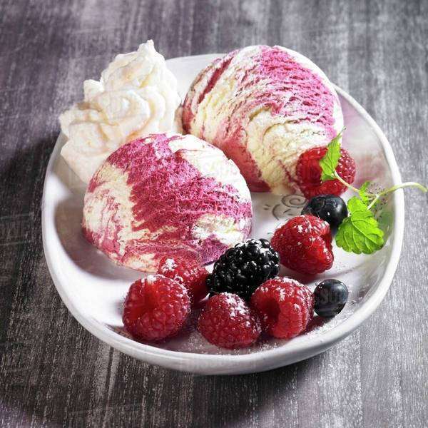 Vanilla and berry ice cream with icing sugar, cream and lemon balm
