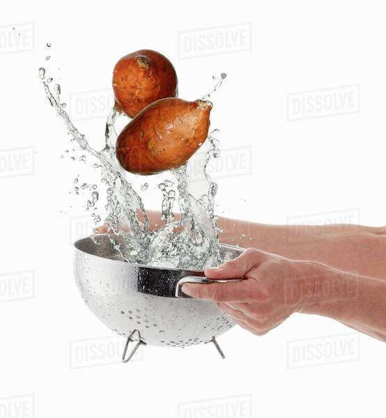 Sweet potatoes being washed Stock Photo Dissolve