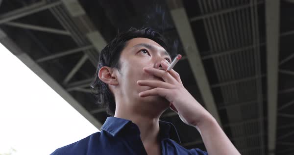 Portrait shot of Japanese man smoking cigarette downtown Tokyo D112_102_201