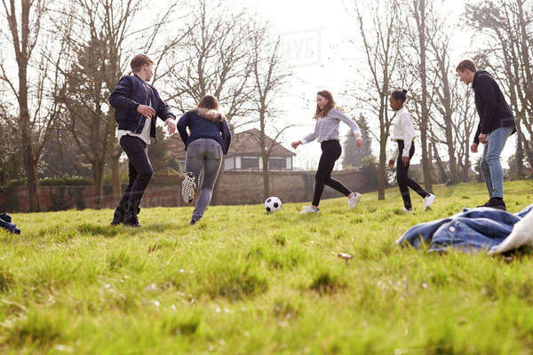 Group of teenagers playing soccer in park together - Stock Photo - Dissolve