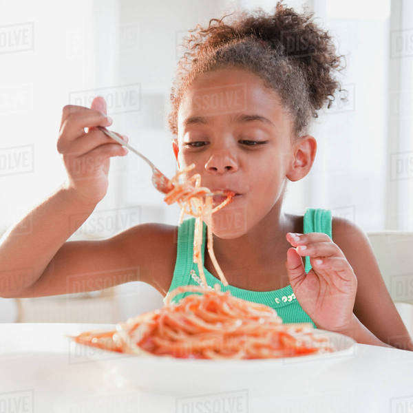 Mixed race girl eating spaghetti Stock Photo Dissolve
