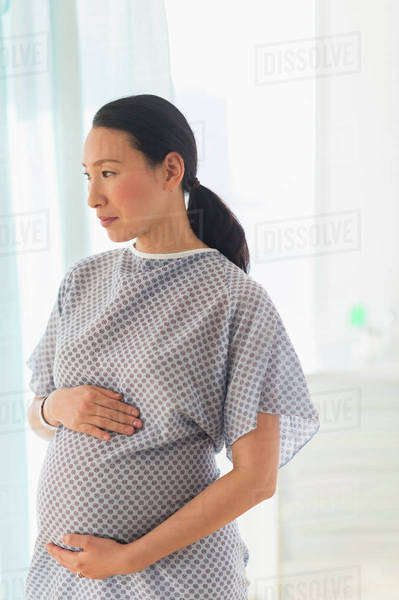 Pregnant Japanese woman in hospital gown - Stock Photo - Dissolve