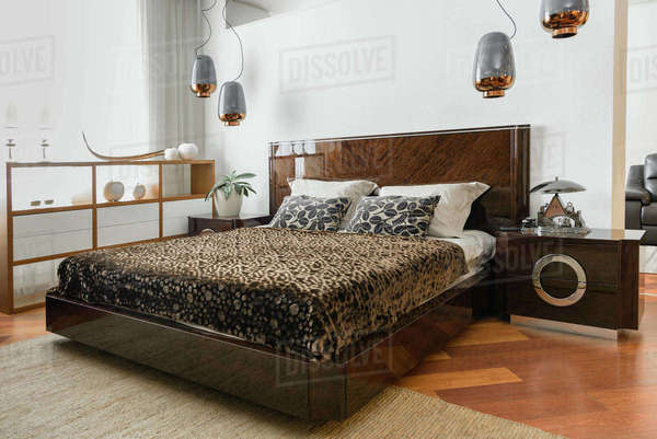 Interior of modern light bedroom with lamps and brown bedsheets ...