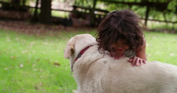 Young Hispanic Boy With Long Hair Playing With A Big Dog In A Park