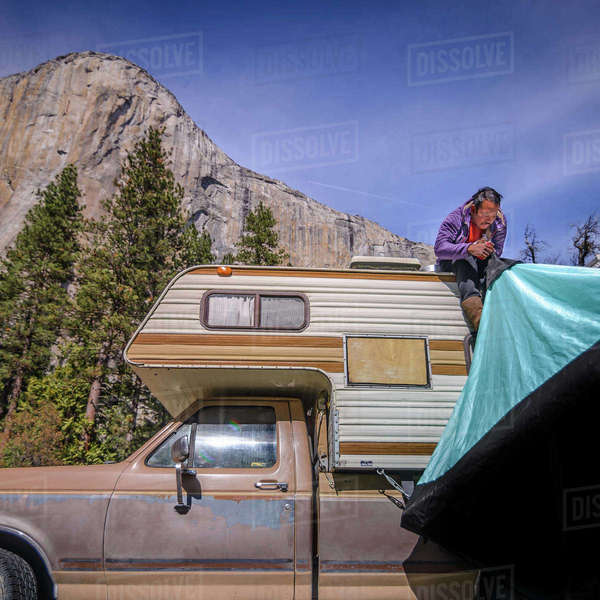 Climber on top of campervan setting up tent, Yosemite National Park