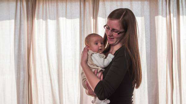 Mother And Baby Posing In Front Of Curtains Medium Shot Of