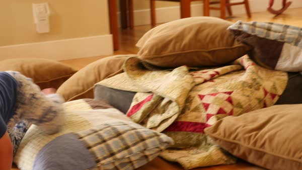 A Toddler Builds A Blanket And Pillow Fort On The Floor Of His