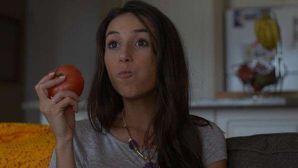 Attractive Woman On Couch Eats Big Red Tomato Close Up Stock