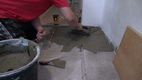 Worker Distributes The Mass Of The Tile Glue Cement With Trowel On