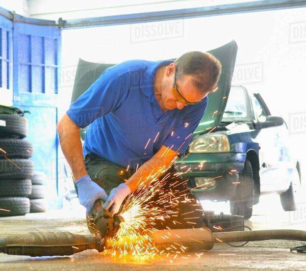 Mechanic cutting exhaust pipe with grinder Stock Photo Dissolve