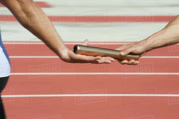 Runners exchanging baton in relay race, cropped - Stock Photo - Dissolve