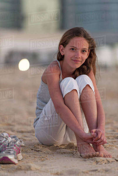 Preteen Girl Sitting On Beach With Barefeet Hugging Knees Stock 