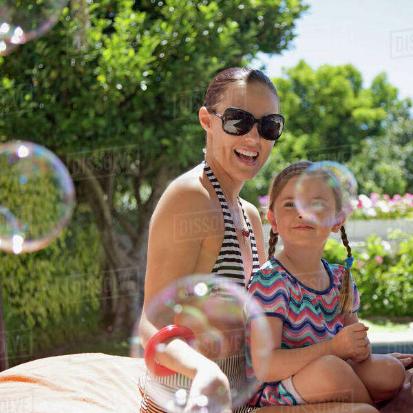 Soap bubbles floating by a mother and daughter sitting together