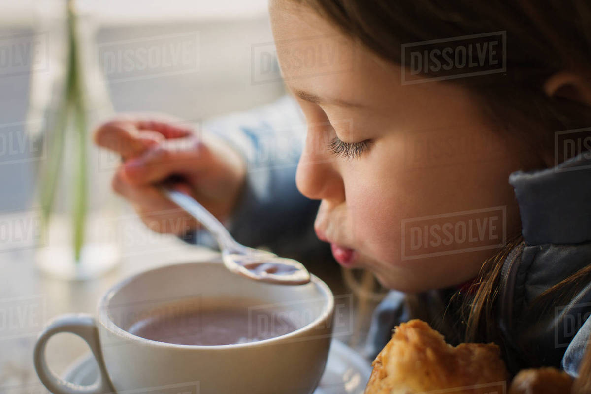 Close up girl blowing on hot soup Stock Photo Dissolve