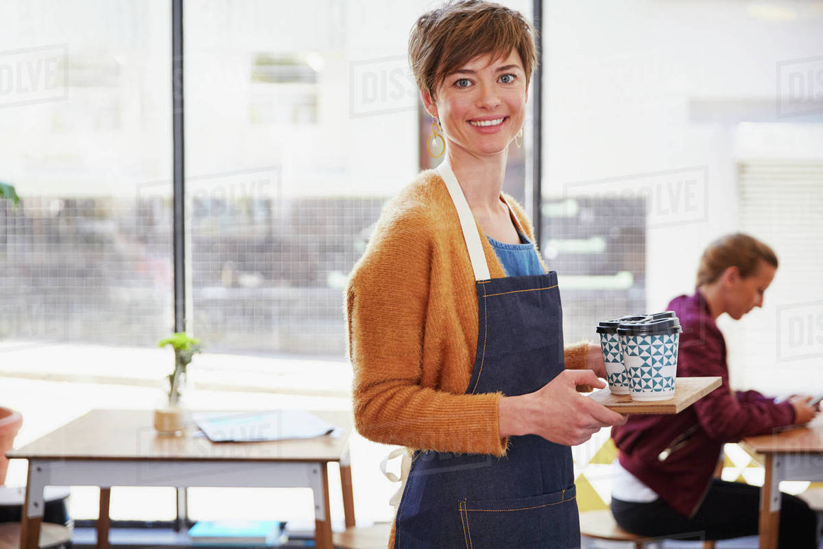 Portrait confident female cafe owner serving coffee on tray in cafe