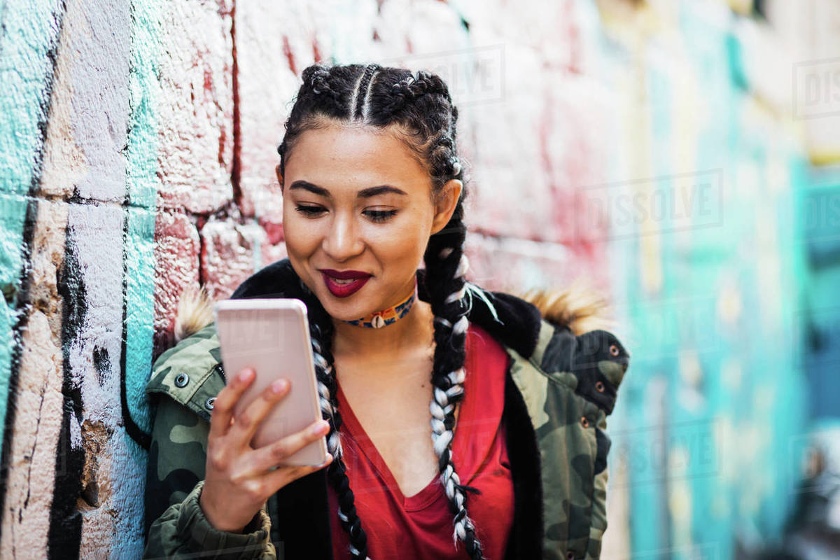 Portugal, Lisbon, Smiling young woman looking at smartphone, leaning against wall Royalty-free stock photo