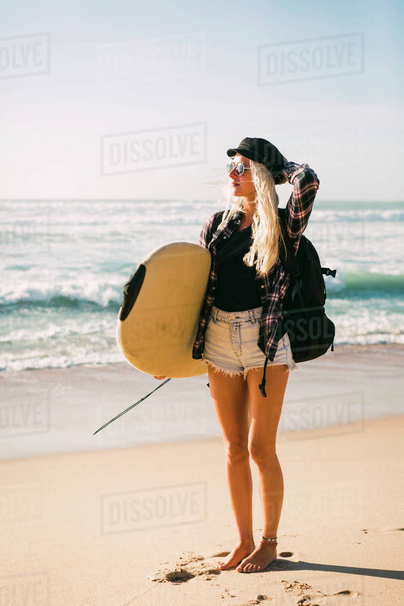 Woman holding surfboard on beach - Stock Photo - Dissolve