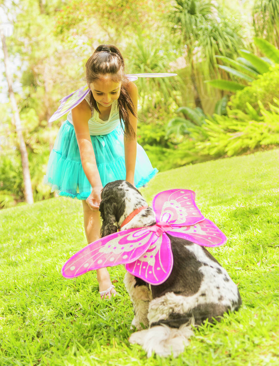 Girl (8-9) wearing fairy costume playing with dog Royalty-free stock photo