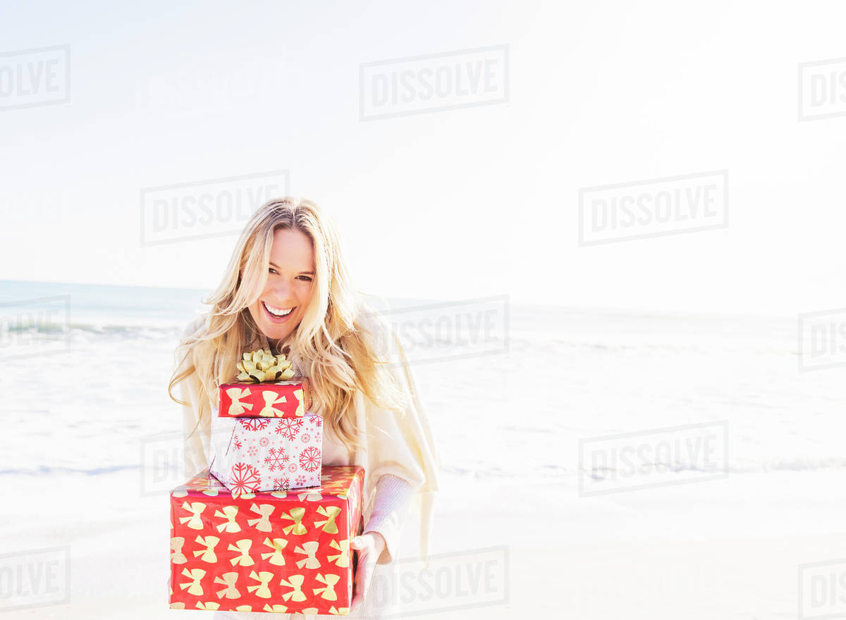 Portrait Of Smiling Woman Holding Presents On Beach Stock Photo Portrait Of Smiling Woman Holding Presents On Beach