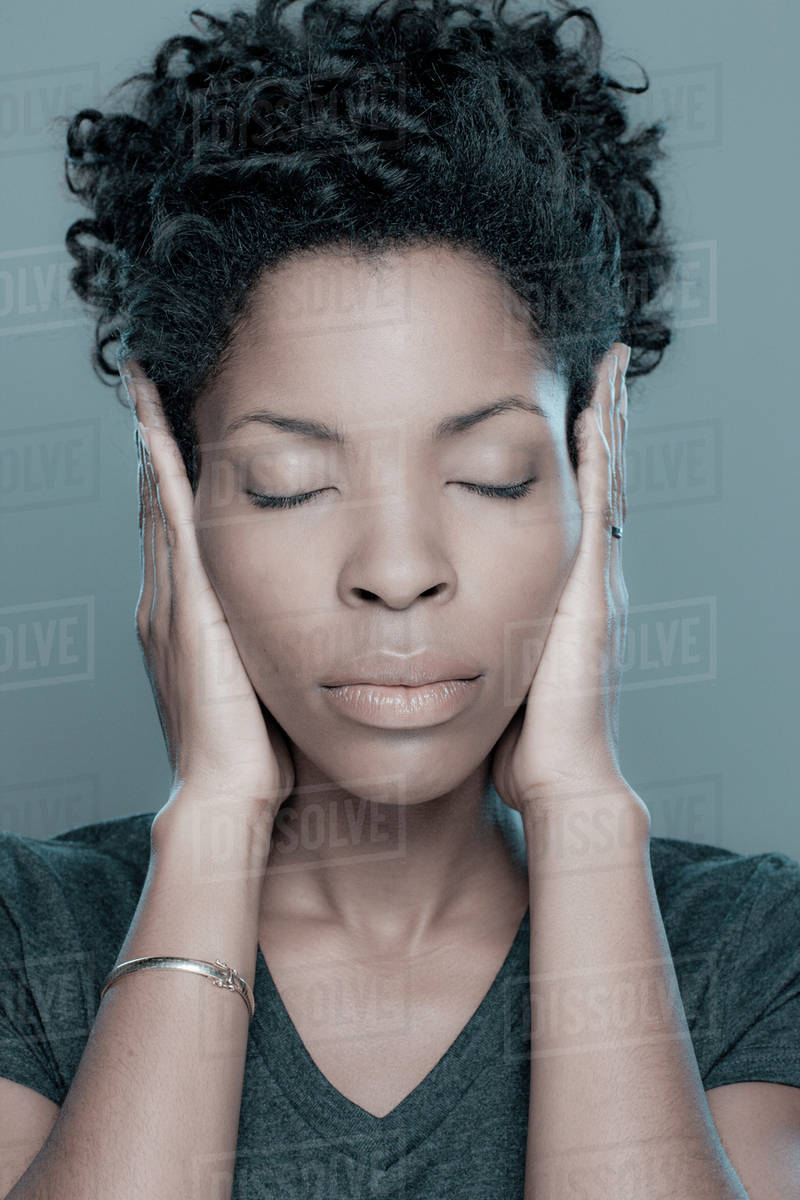 Studio shot of young woman with hands covering ears Stock Photo