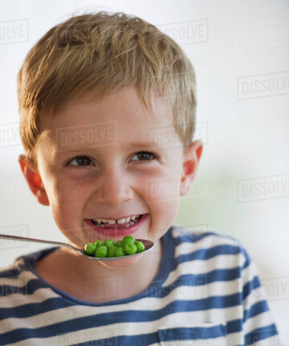 Young boy eating peas Stock Photo Dissolve