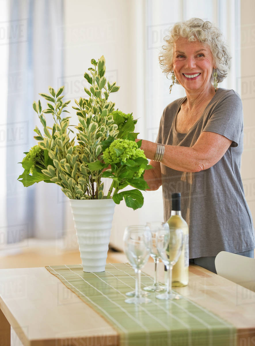 Woman arranging flowers in a vase Stock Photo Dissolve