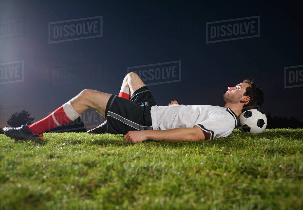 Soccer player resting on ball Stock Photo Dissolve