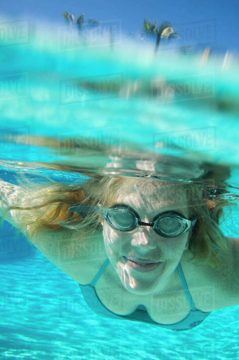 Woman wearing goggles underwater Stock Photo Dissolve