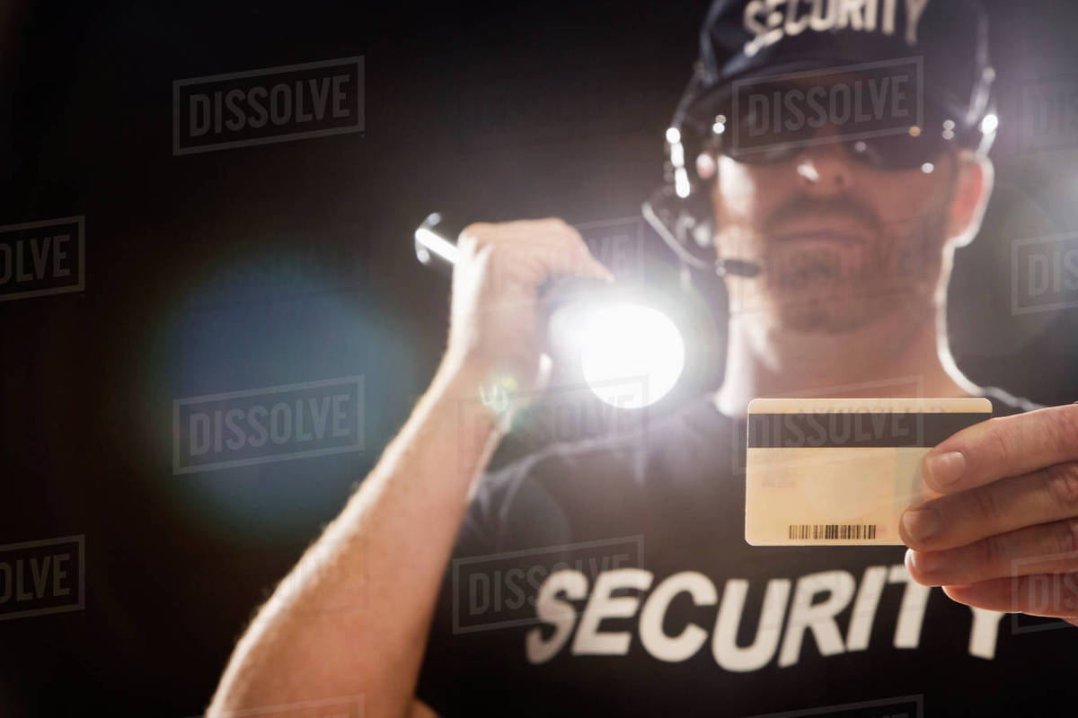 Bouncer checking identification with flashlight Stock Photo Dissolve