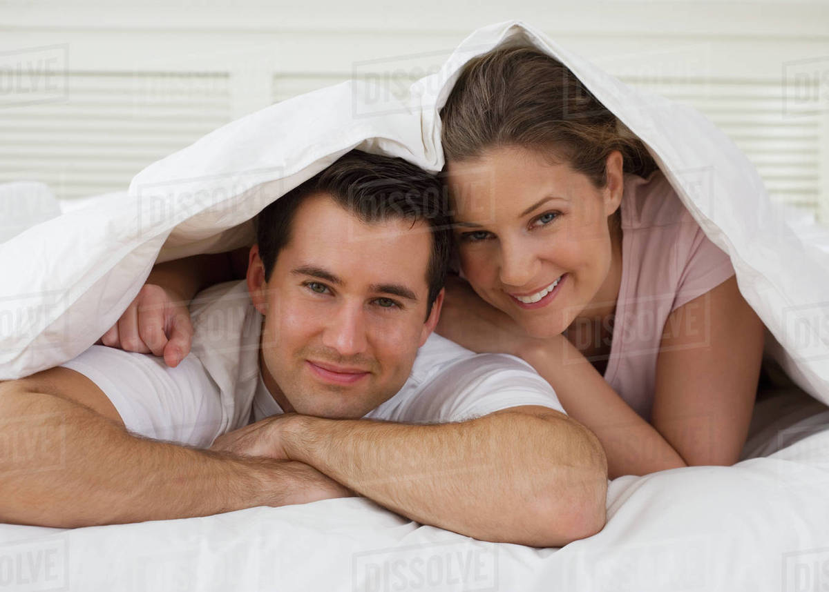 Portrait of couple under bed covers Stock Photo Dissolve