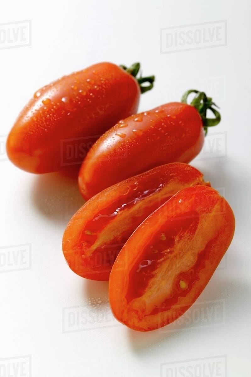 Three grape tomatoes, one halved Stock Photo Dissolve