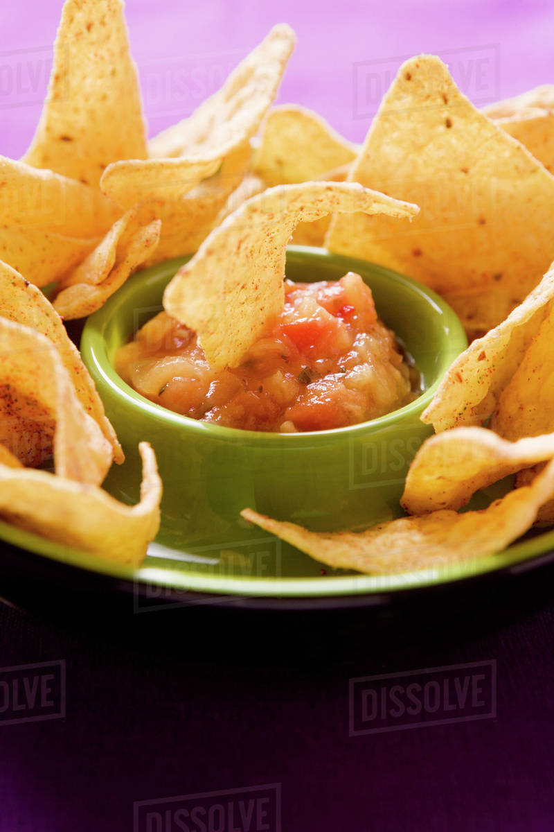 Tortilla chip dipped in tomato salsa Stock Photo Dissolve