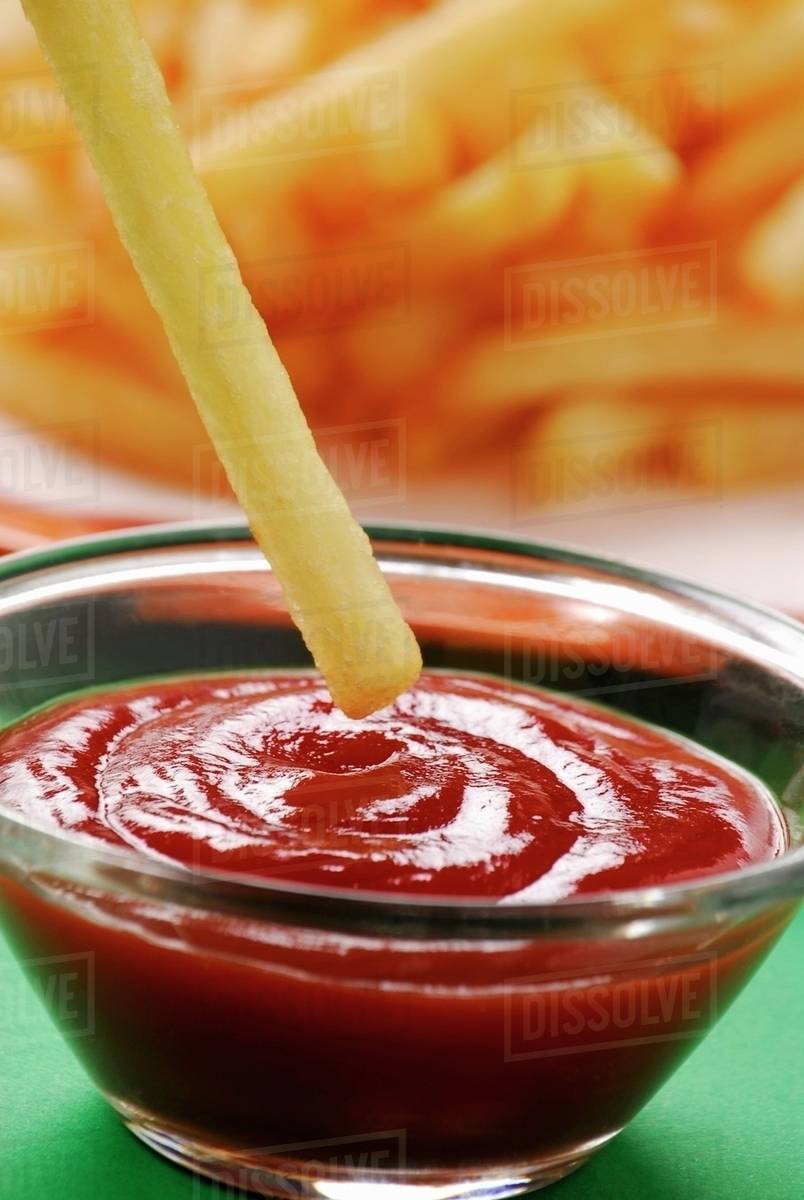 Dipping a chip in ketchup Stock Photo Dissolve