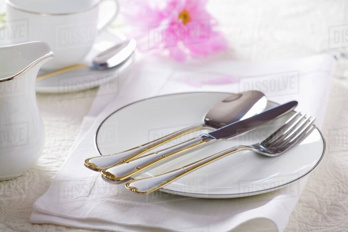 Goldrimmed plate with cutlery Stock Photo Dissolve