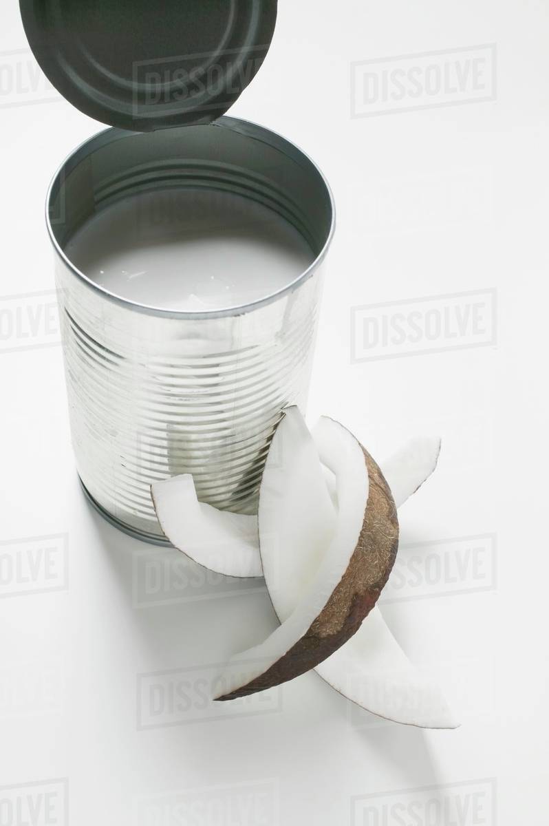 Coconut milk in a tin, wedge of coconut beside it Stock Photo Dissolve