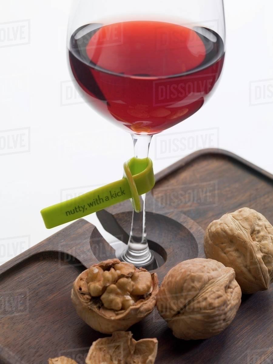 Glass of red wine with plastic label describing the wine, nuts Stock
