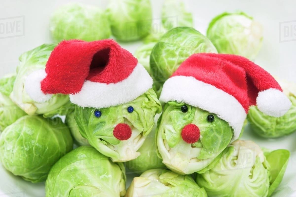 Two Brussels sprouts with faces wearing Christmas hats Stock Photo