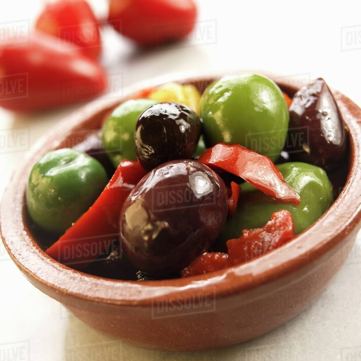 Marinated olives and peppers in a terracotta dish Stock Photo Dissolve