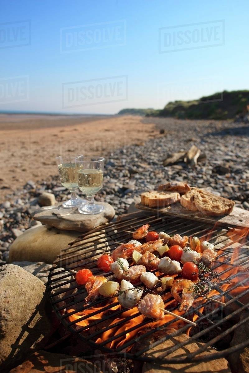 Fish skewers on a barbecue on a beach Stock Photo Dissolve