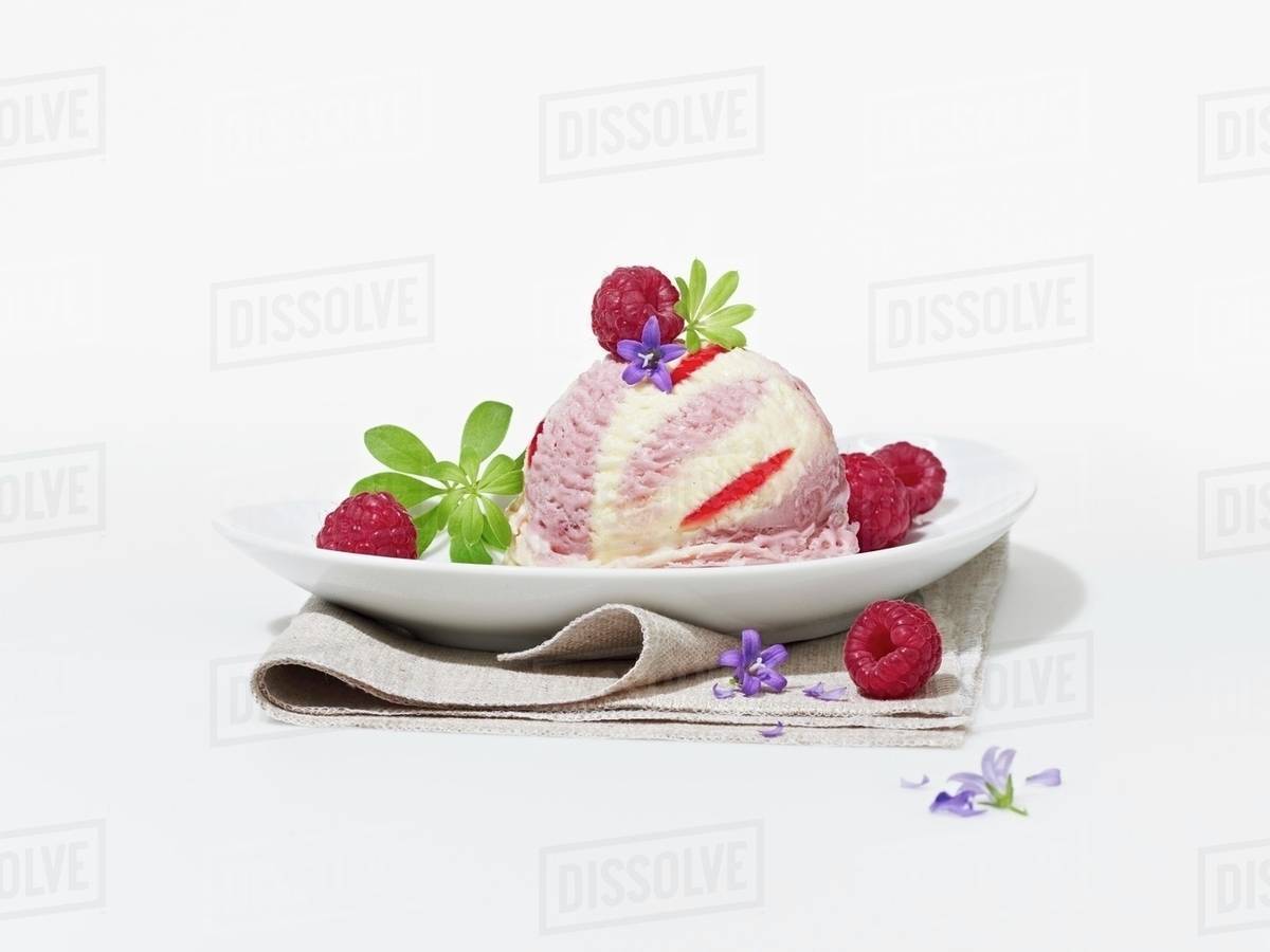 A raspberry ice cream bomb with raspberries, woodruff and flowers