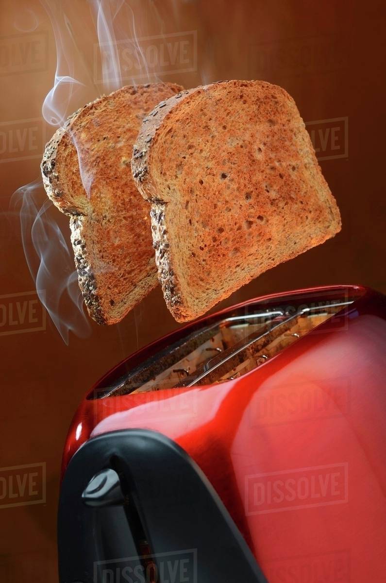 Smoking wholemeal toast jumping out of a red toaster Stock Photo