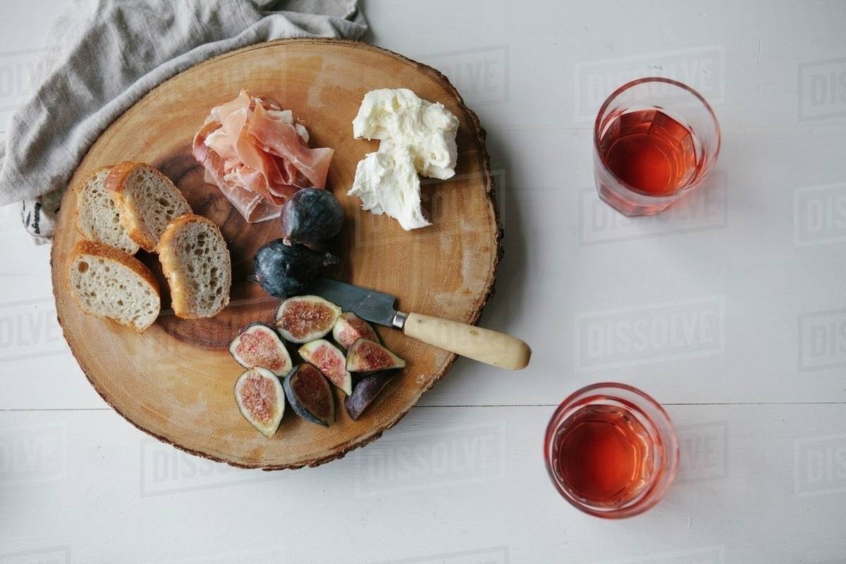 Parma ham, figs, bread and cream cheese on a wooden platter Stock