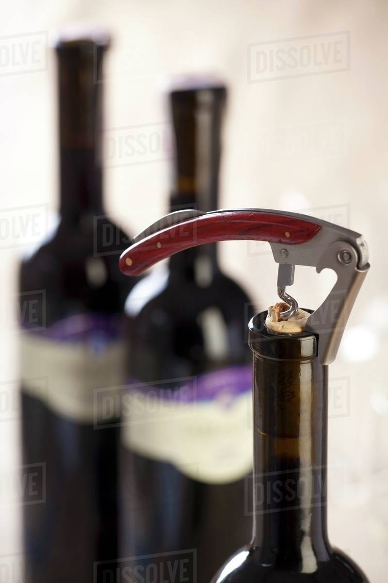 Bottle of red wine with corkscrew Stock Photo Dissolve