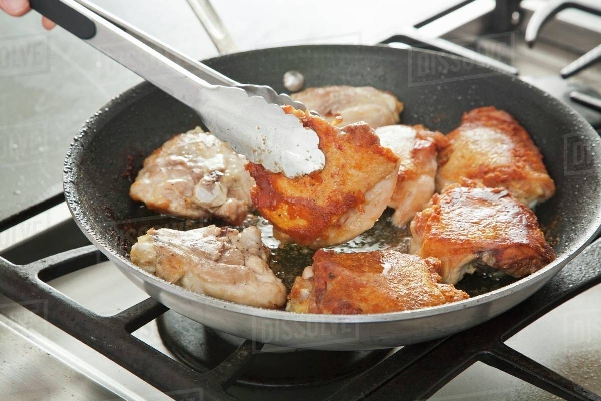 Browning Chicken in a Skillet; Flipping with Tongs Stock Photo Dissolve
