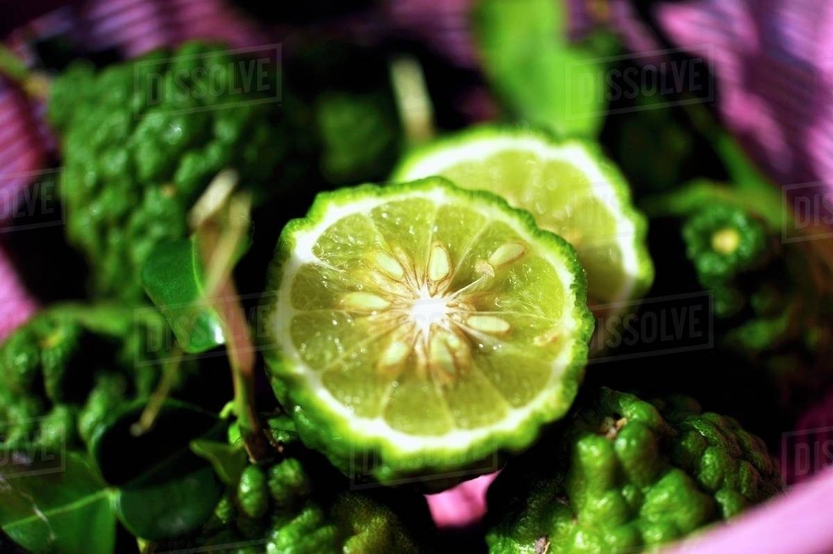Thai limes with wrinkled skin, whole and halved Stock Photo Dissolve