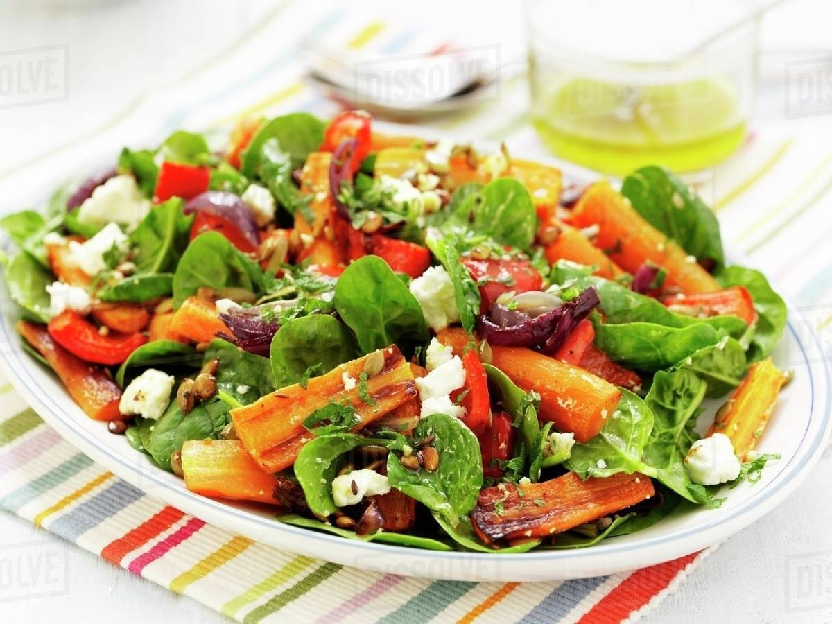 A colourful plate of salad with roasted carrots, dried tomatoes, red