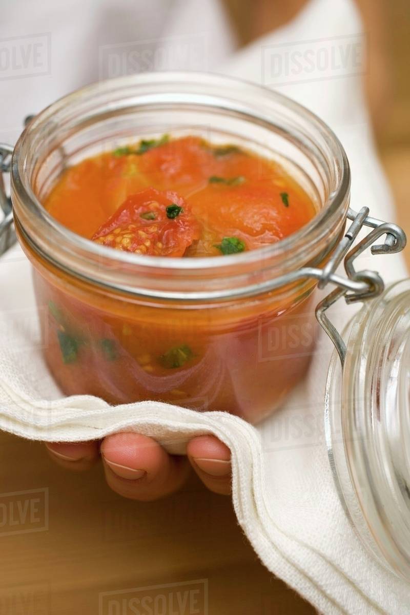 Hand holding preserving jar of tomato sauce Stock Photo Dissolve
