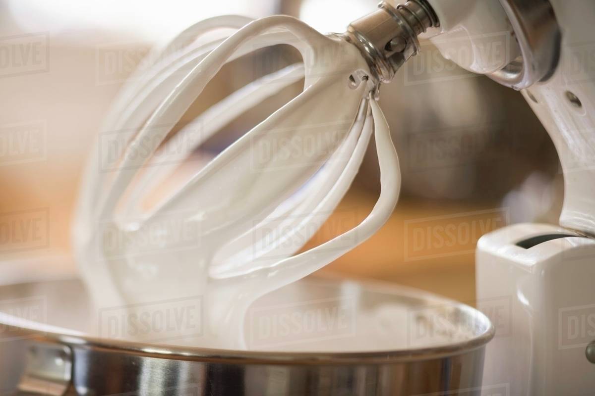 Whipped cream on balloon whisk of food mixer Stock Photo Dissolve